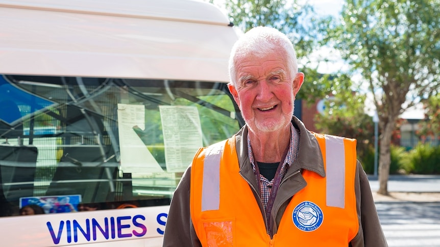 Frank Mullins smiles at the camera wearing a high-vis vest and holding a thermos.
