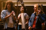 Colour still of Gwilym Lee, Ben Hardy and Rami Malek in recording studio in 2018 film Bohemian Rhapsody.
