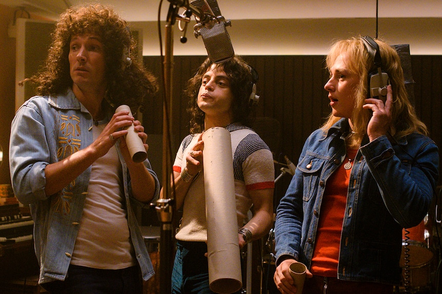 Colour still of Gwilym Lee, Ben Hardy and Rami Malek in recording studio in 2018 film Bohemian Rhapsody.