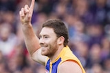 A happy Eagles defender Jeremy McGovern celebrates a goal with a finger in the air wearing West Coast's alternate yellow jumper.