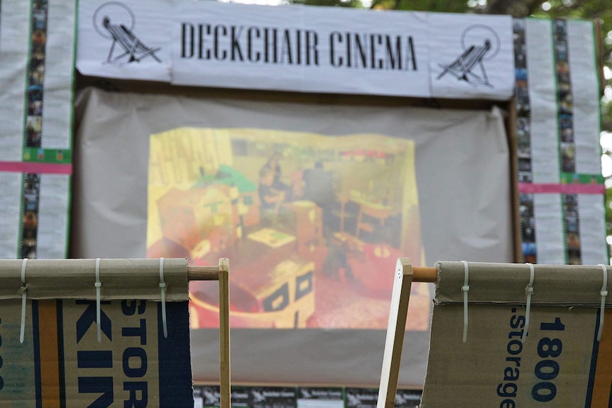 Two deckchairs made out of cardboard boxes in front of a replica Deckchair Cinema made of cardboard and butchers paper.