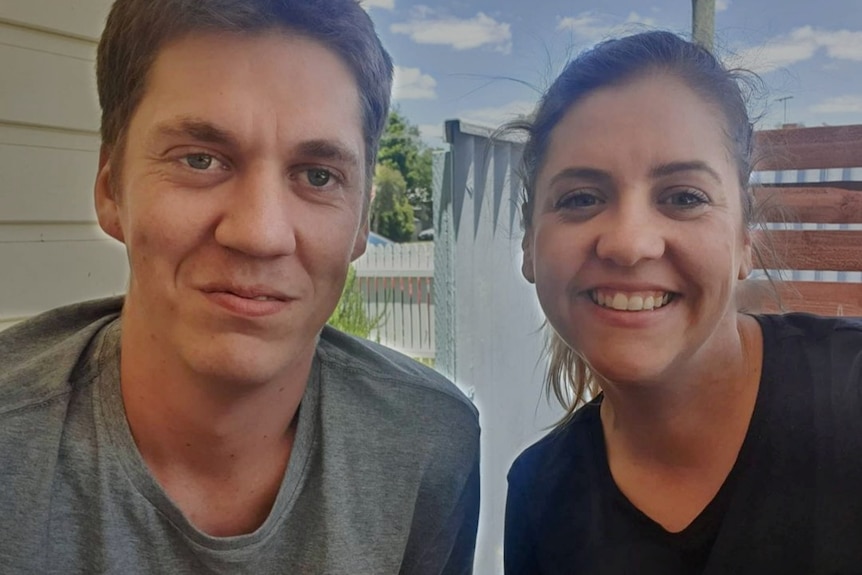 A man smiles at the camera next to a woman who is his sister.