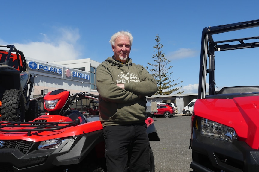 man leans on quad bike and stands next to side by side