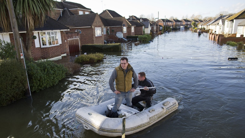 Residents use a boat to move along a flooded street in Egham on February 11, 2014