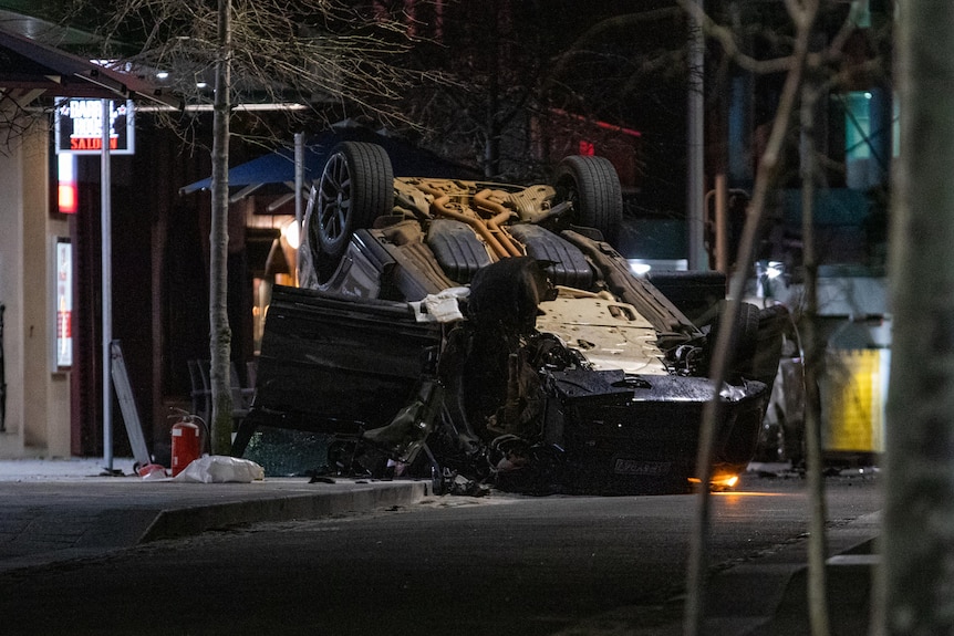 An overturned car in the middle of a road at night.