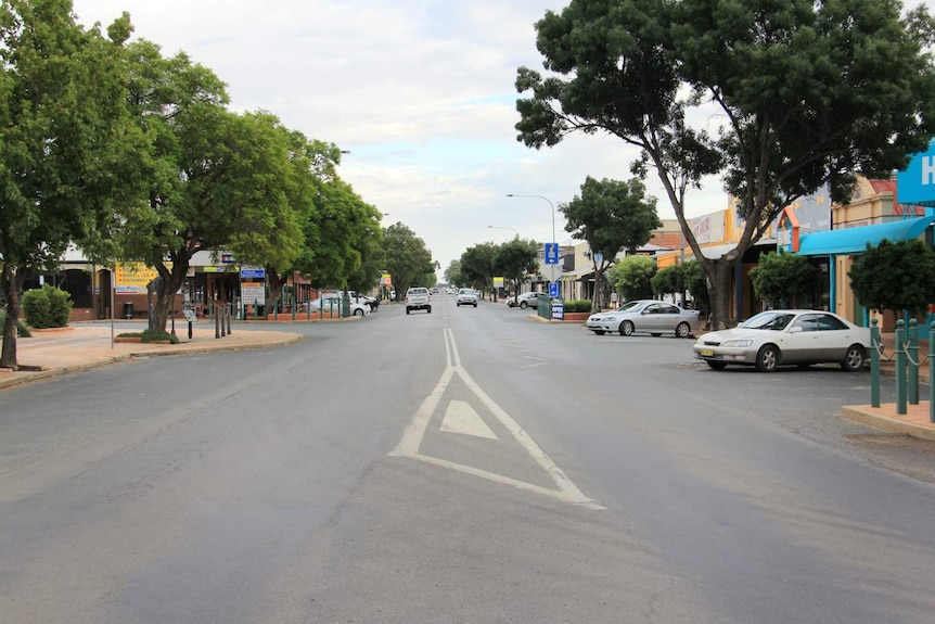 A street with two cars driving on it.