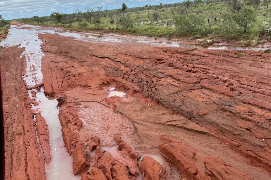 a red dirt road covered in mud and floodwaters