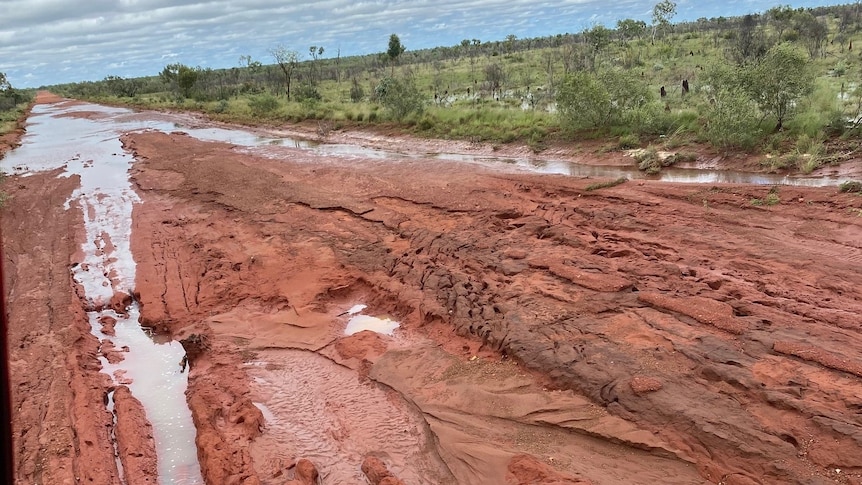 a red dirt road covered in mud and floodwater