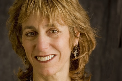 A photo of Nancy Sherman, smiling wearing a black jacket and a necklace