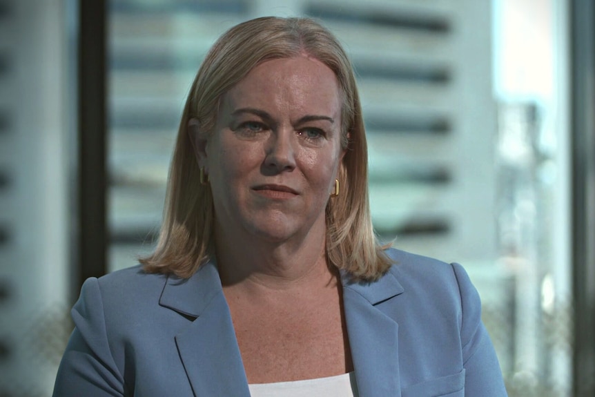 Woman with short blonde hair wearing a blue blazer. 