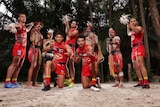 Gold Coast players wearing the club's Indigenous round jersey with men in ceremonial clothing and body paint. 