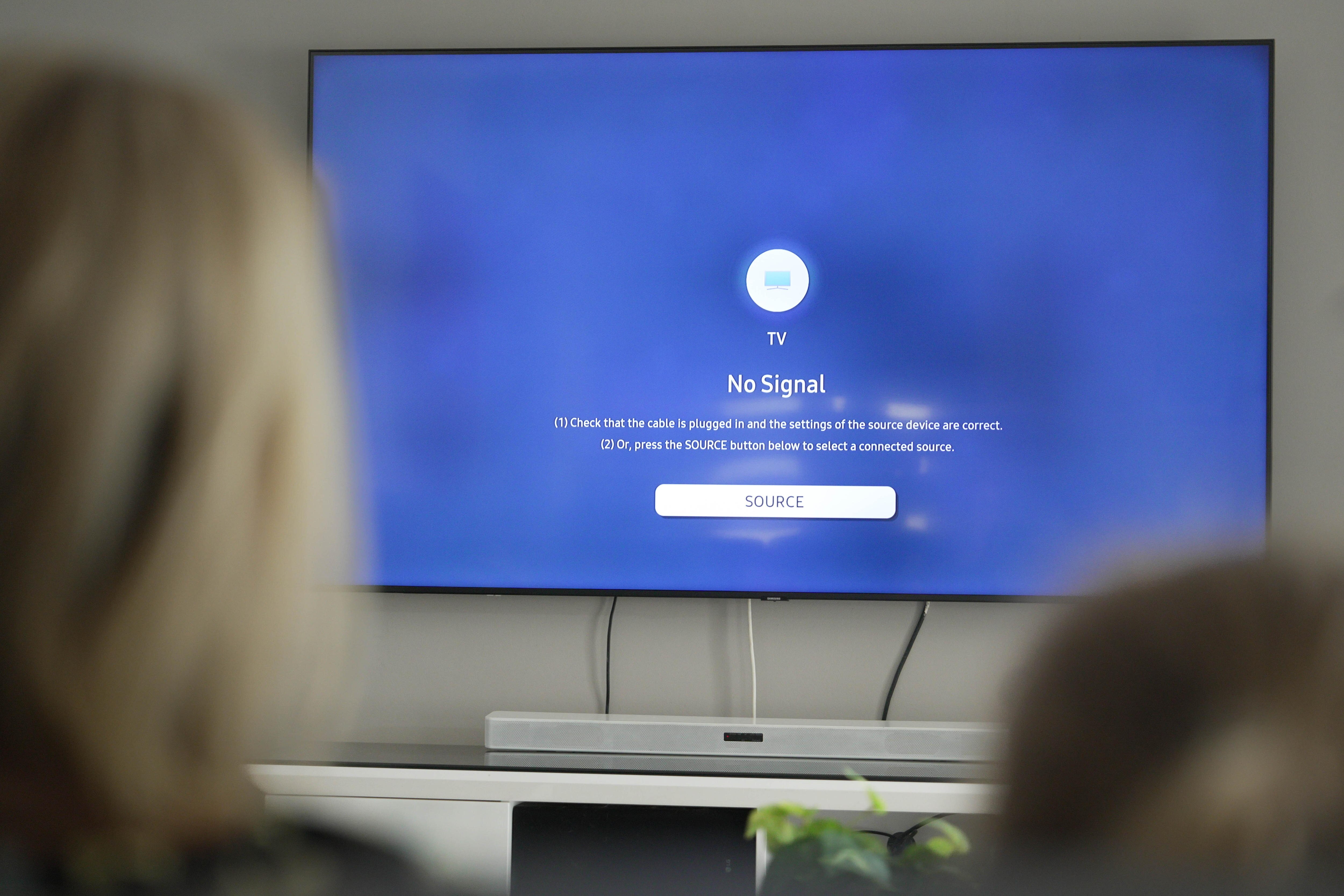 Tomas de la parte posterior de la cabeza de una mujer con cabello rubio y un niño con cabello más oscuro mirando un televisor de pantalla azul que dice 