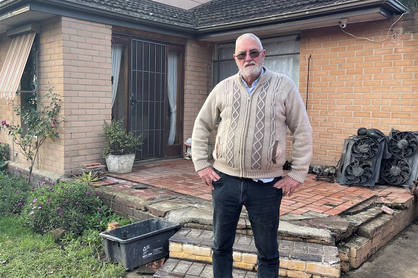 A man stands outside his flood-damaged brick house