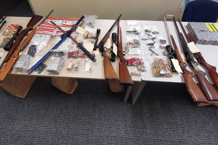 A collection of guns, and ammunition laid out on a table.