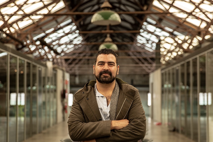 Colour photograph of Performance Space artistic director Jeff Khan with arms folded and standing in warehouse space.