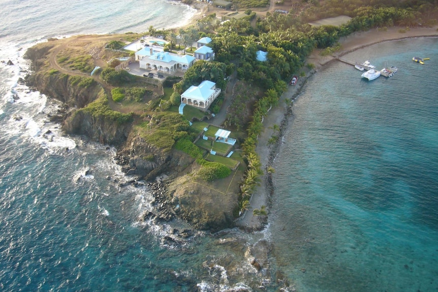 An aerial shot of a tropical island with a sprawling estate built at the cliff's edge