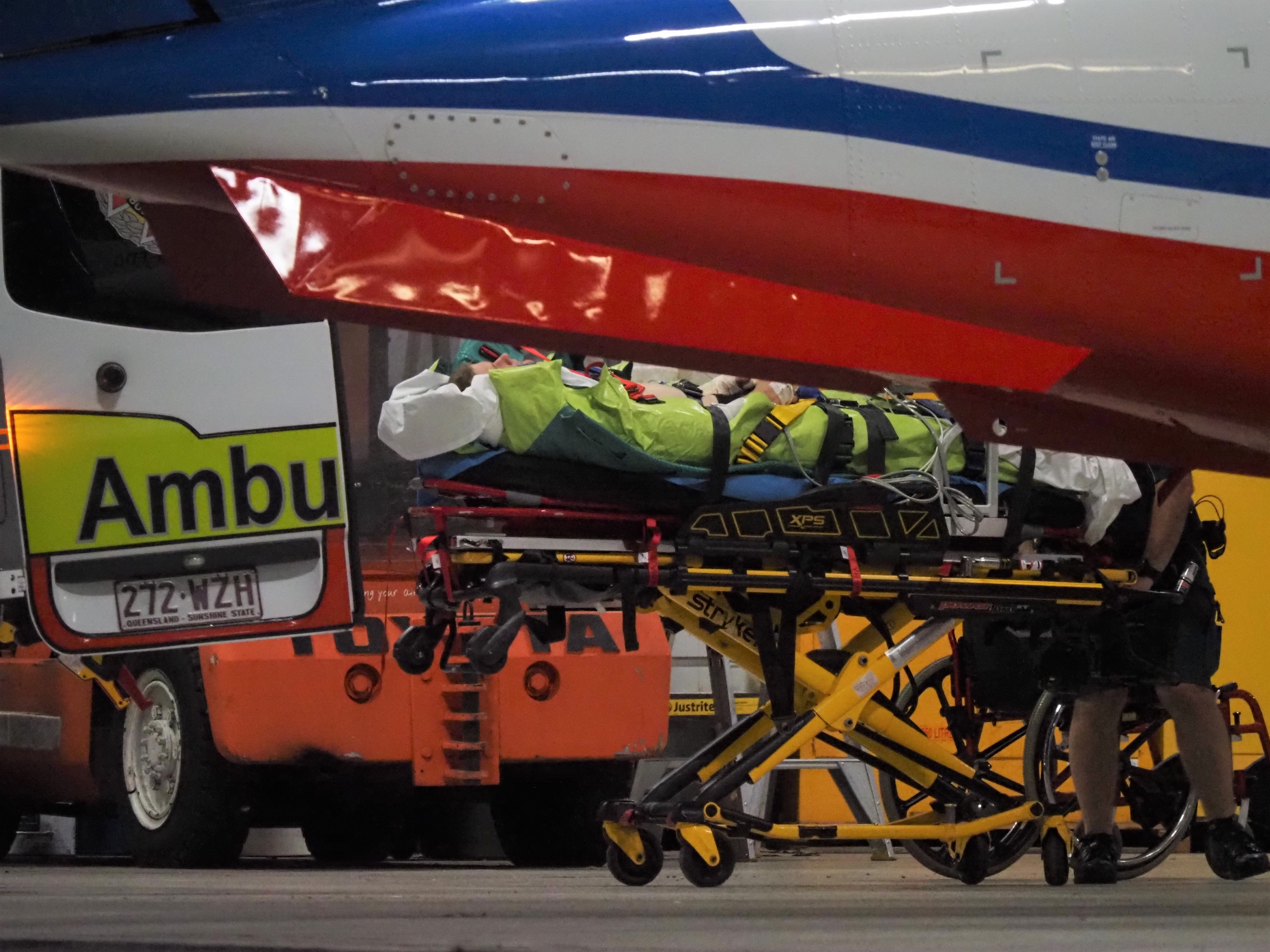 Man lying down in stretcher near ambulances.