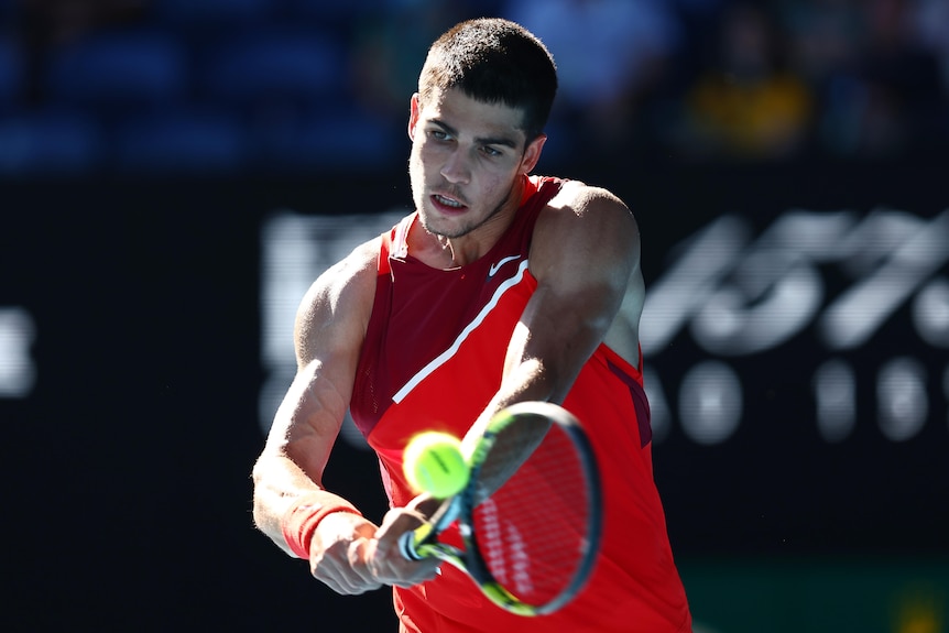 A Spanish male tennis player hits a double-fisted forehand during an Australian Open match.