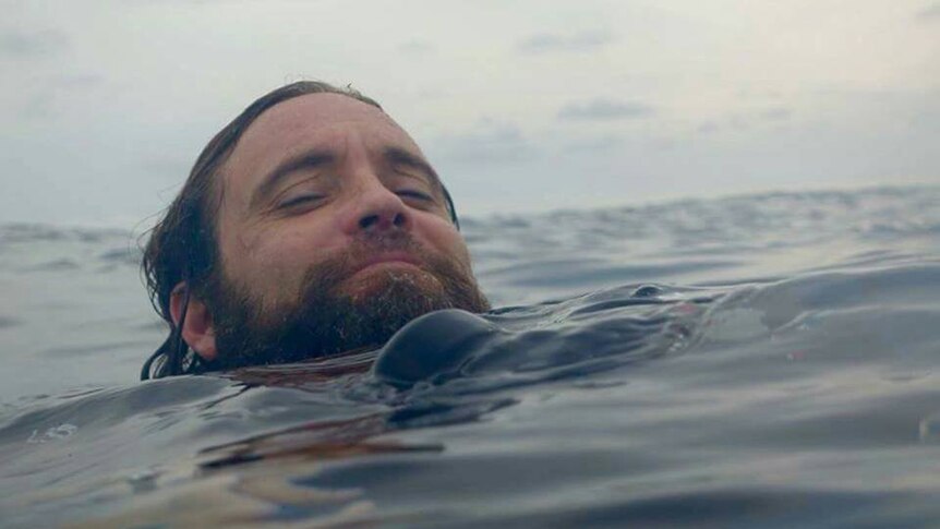 Perth man Michael Kearns swims in the ocean with his head above water.