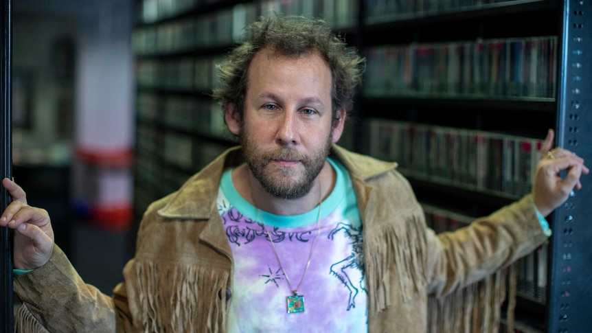 Singer-songwriter Ben Lee pictured in the Triple J Music Library wearing a tie-dye tee and fringed suede jacket