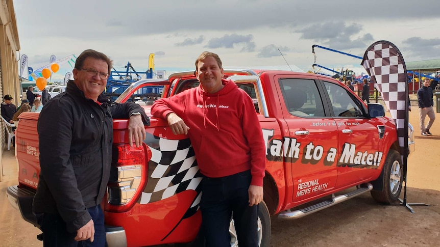 Two men standing in front of a red ute at a field day in Western Australia