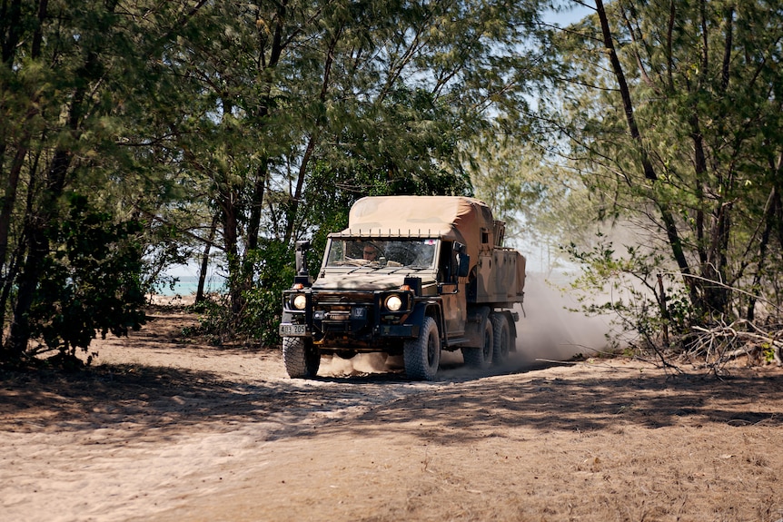 An Australian army vehicle driving through bush.