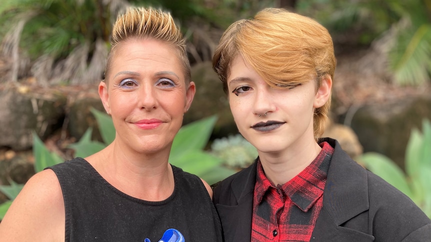 Mandy has short, blonde, spiked up hair. Her teenager, Void, is wearing black lipstick and eyeliner.