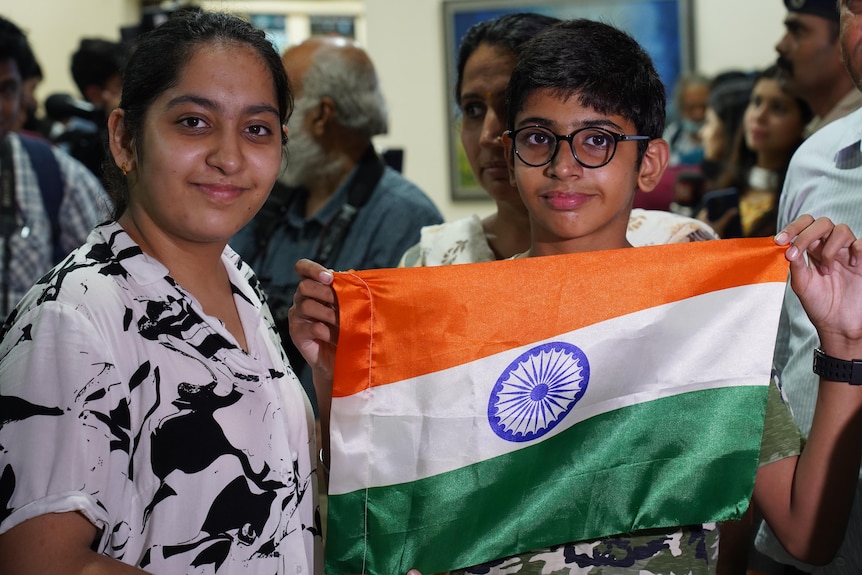 A woman stands next to a boy holding the Indian national flag.