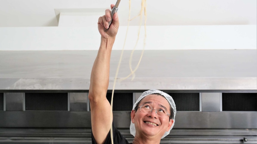 Shing Hee Ting cooking noodles in his kitchen