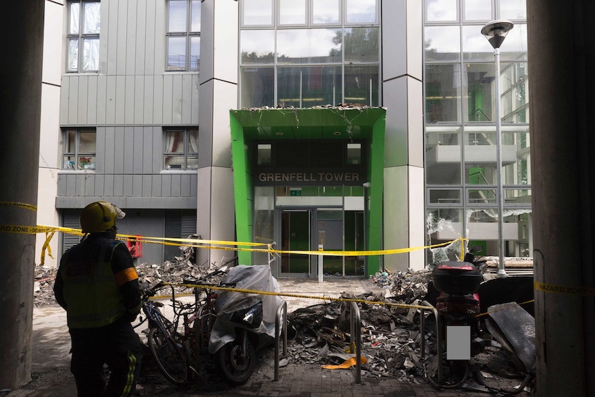 A view of a green, modern looking entrance to Grenfell Tower that has been cordoned off with yellow tape.
