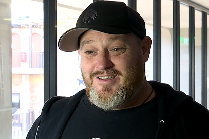 A man in a black hat and a black shirt being interviewed on camera.