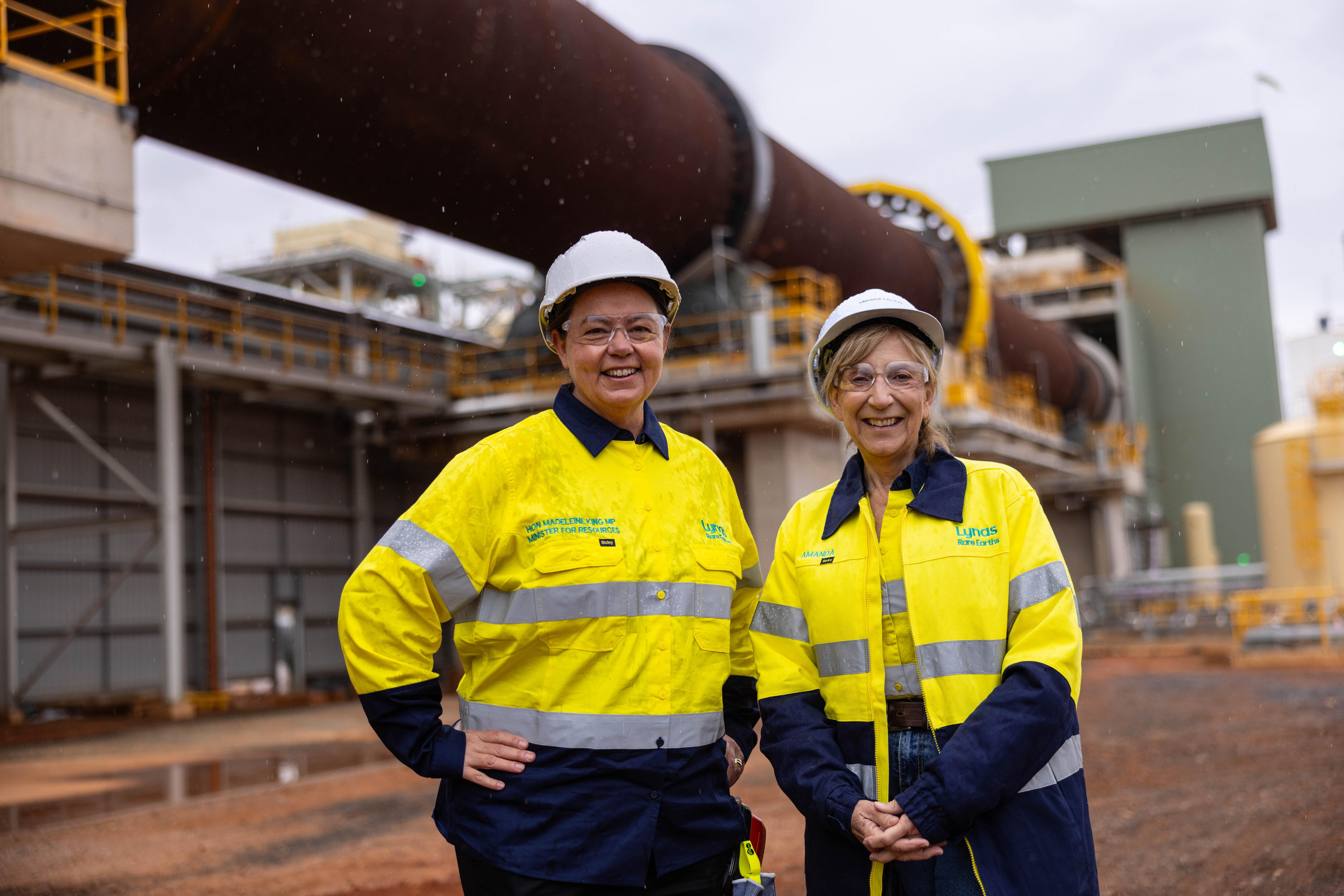 Dos mujeres con cascos y gafas de alta visibilidad en una refinería de tierras raras. 