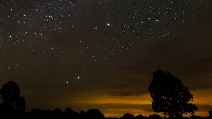 Dark sky with stars and meteor streak.