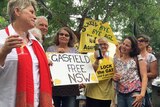 A group of people hold champagne and signs with messages such as 'Bye Bye AGL' and 'Gasfield Free NSW'