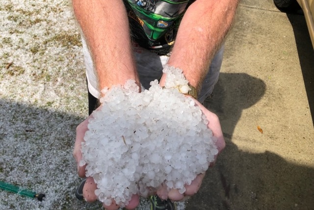 A man holds both his palms out full of hail.
