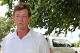 Shane Nouwens stands outside his taxi under a tree
