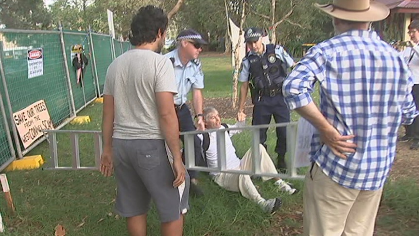 A man on the ground with police holding his hands.