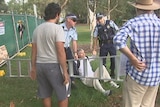 A man on the ground with police holding his hands.