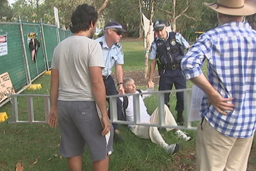 A man on the ground with police holding his hands.