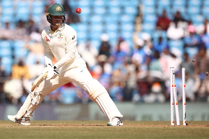 An Australian male batter looks back at his stumps after being bowled by India.