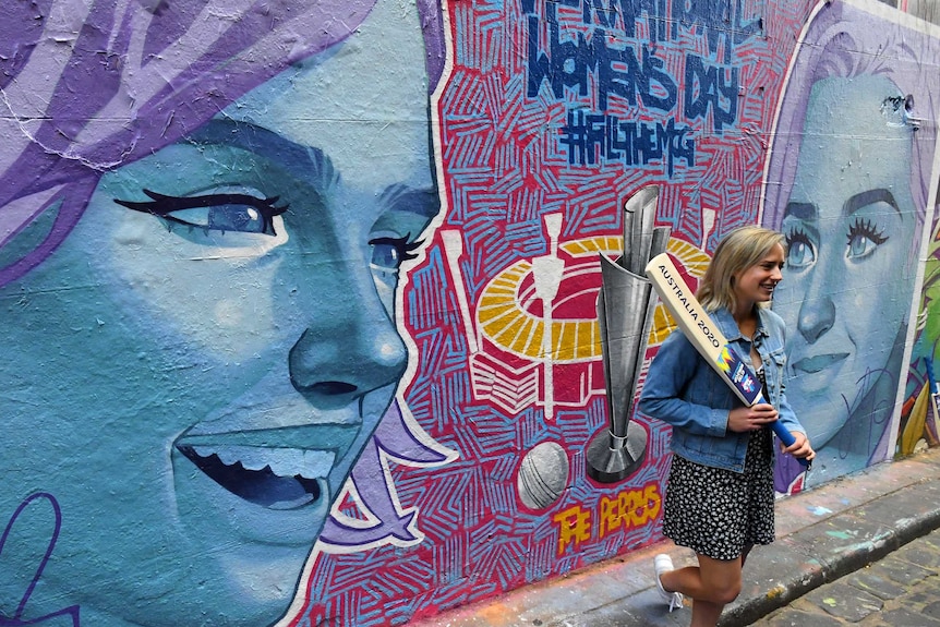 Ellyse Perry holds a cricket bat in front of a mural of herself and Katy Perry advertising the Twenty20 Women's World Cup final.