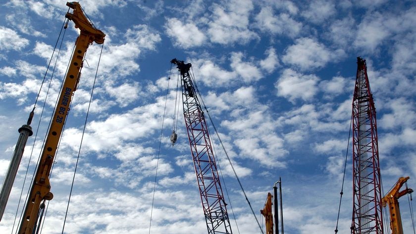 Cranes and construction equipment stand at a construction site.