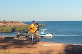 A Broome Shire Council ranger erects a crocodile warning sign at Town Beach.
