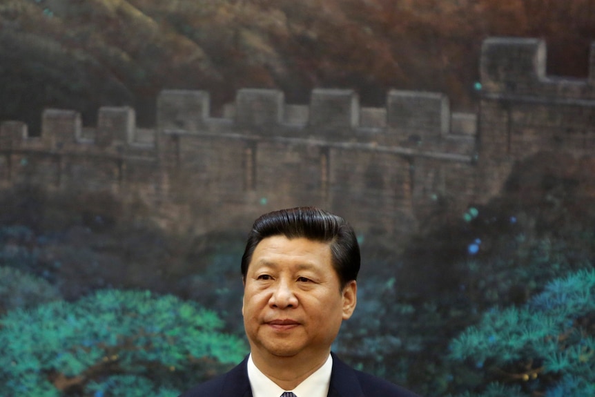 Xi Jinping stands in front of a painting of the Great Wall of China 