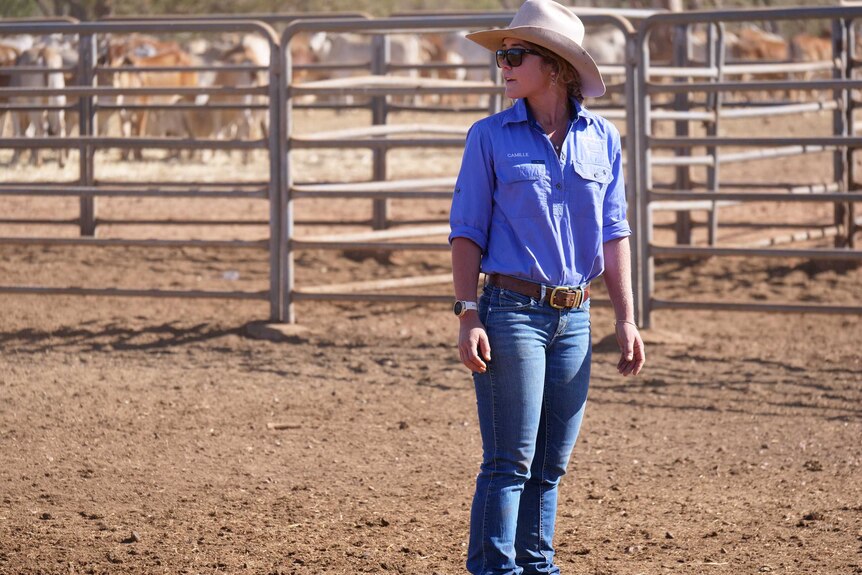 Lady standing in cattle yard wearing hat and purple shirt