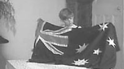 Black and white photo of young boy holding the Australian Flag