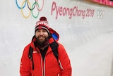 Christopher Spring standing in a bobsled course with the words PyeongChang 2018 behind him.