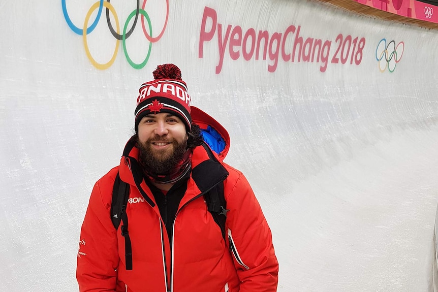 Christopher Spring standing in a bobsled course with the words PyeongChang 2018 behind him.