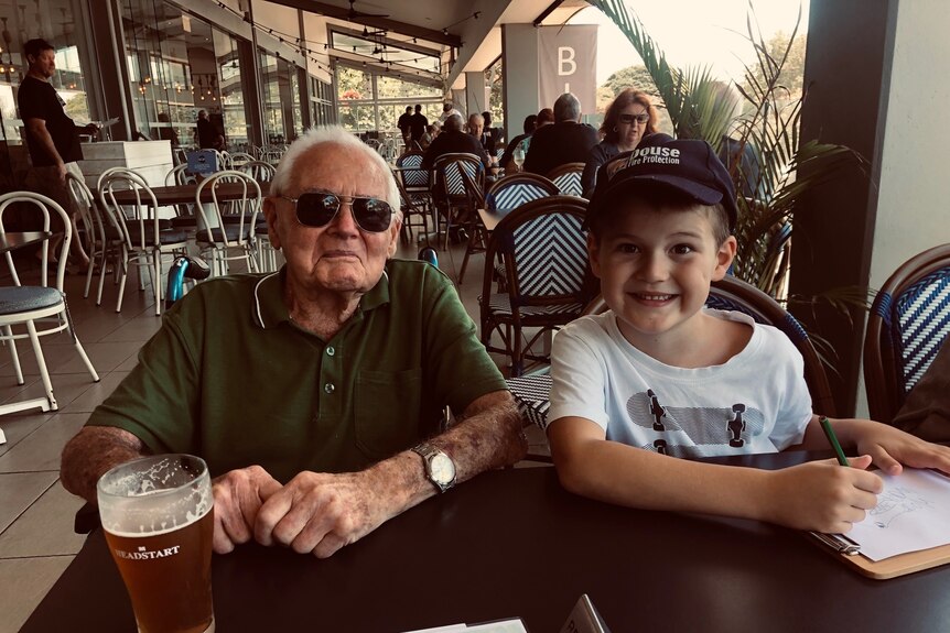 Elderly man and grandson sitting outside a restaurant.