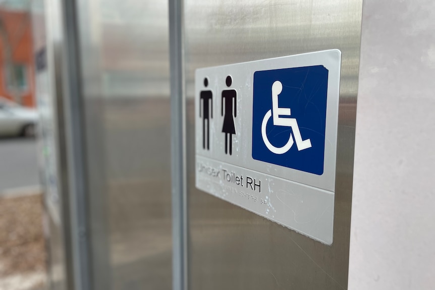 A sign with symbol for male, female and disabled toilets on a silver door